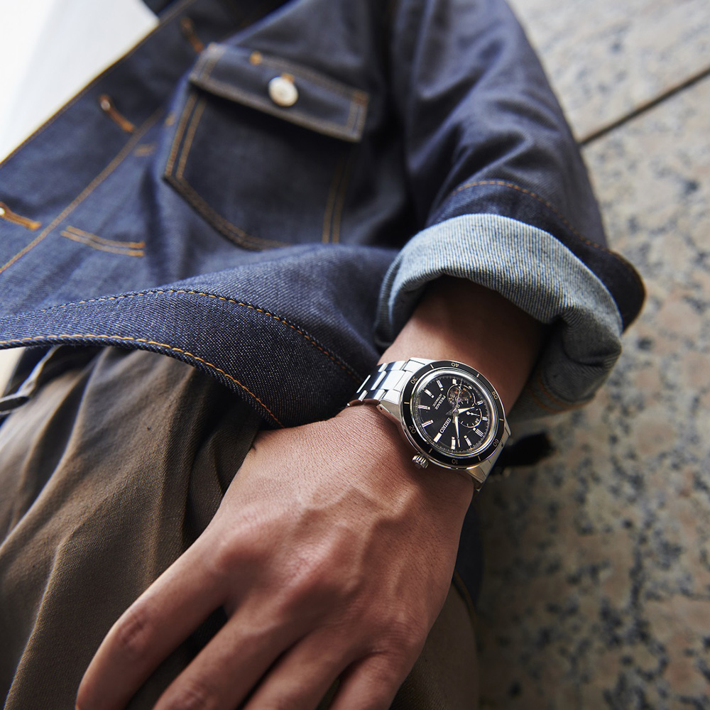 Pesquisar colecção de relógios Seiko por categoria (imagem com zoom -in no pulso de um homem descontraído, encostado a uma parede de pedra, com um relógio Seiko em aço no pulso).