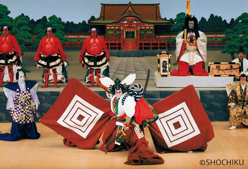 Cena de peça de teatro Kabuki com Ebizo Ichikawa no centro do palco.