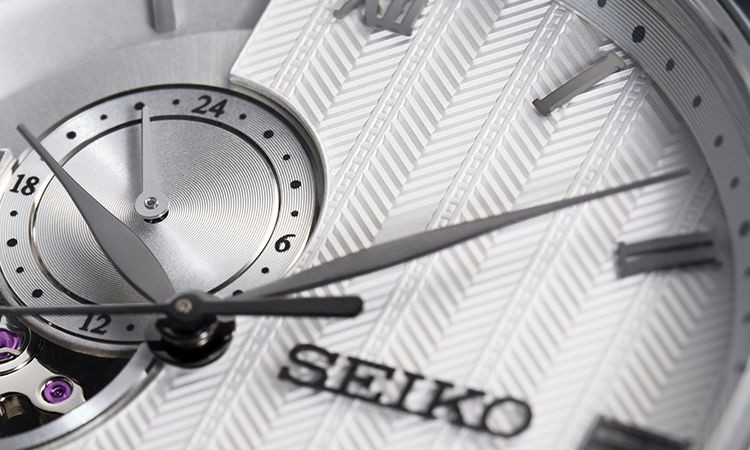 Detalhe do mostrador de um relógio Seiko Presage da série Jardins Japoneses, com o fundo com um padrão geométrico em relevo.